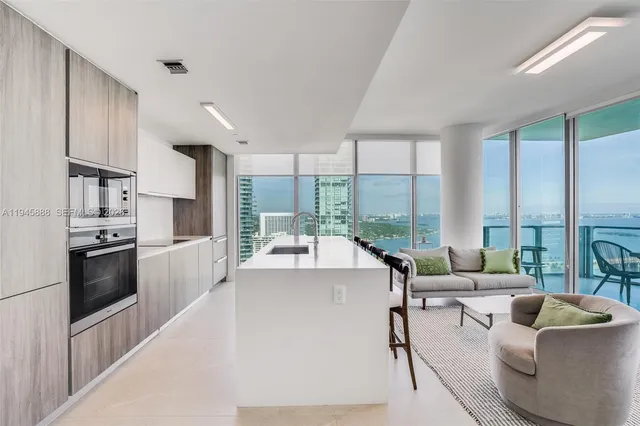a large white kitchen with a large window and stainless steel appliances