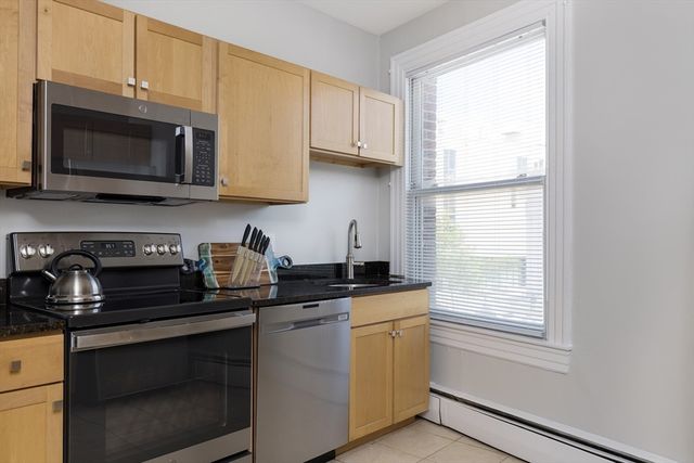 a kitchen with stainless steel appliances granite countertop white cabinets a stove a sink and a microwave