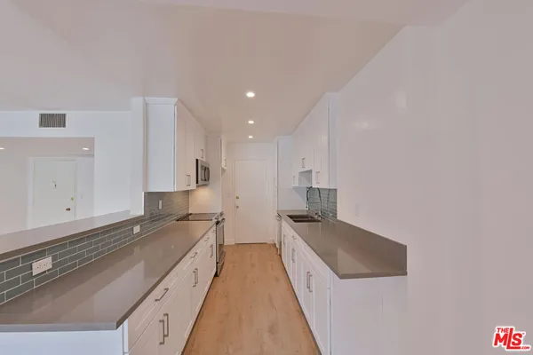 a large white kitchen with stainless steel appliances granite countertop a sink and a stove