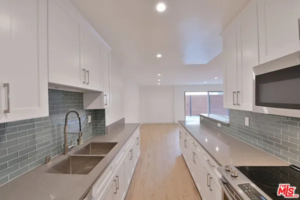 a large kitchen with stainless steel appliances granite countertop a sink a stove and a microwave