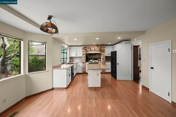 a open kitchen with stainless steel appliances kitchen island wooden floors and refrigerator