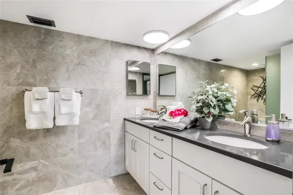 a bathroom with a double vanity sink mirror and shower