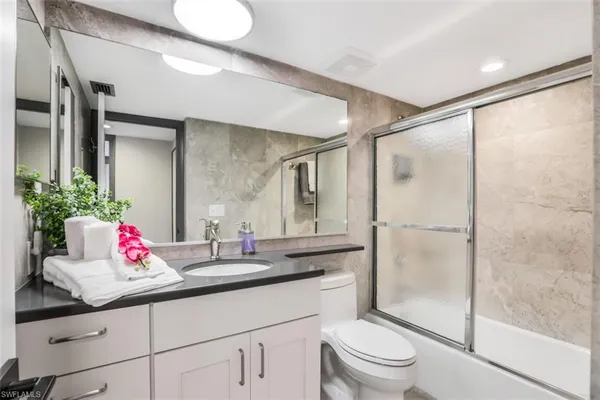 a bathroom with a granite countertop sink mirror toilet and shower