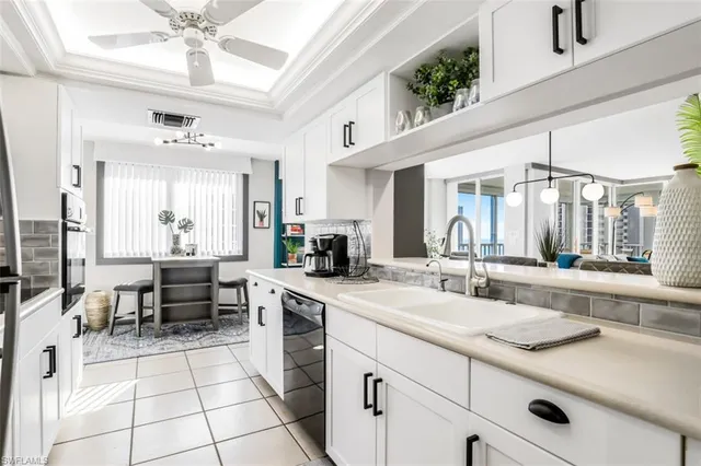 a large white kitchen with a large window and stainless steel appliances