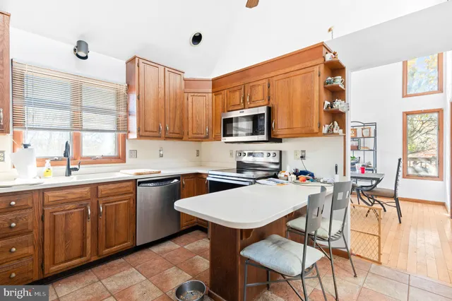 a kitchen with a refrigerator a stove a sink dishwasher with a dining table and chairs with wooden floor