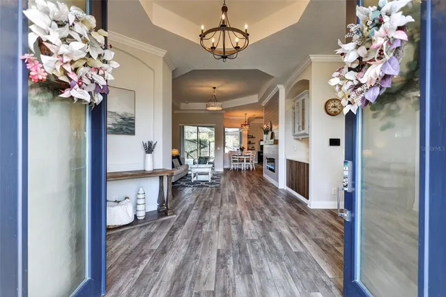 a view of a hallway with wooden floor and a chandelier