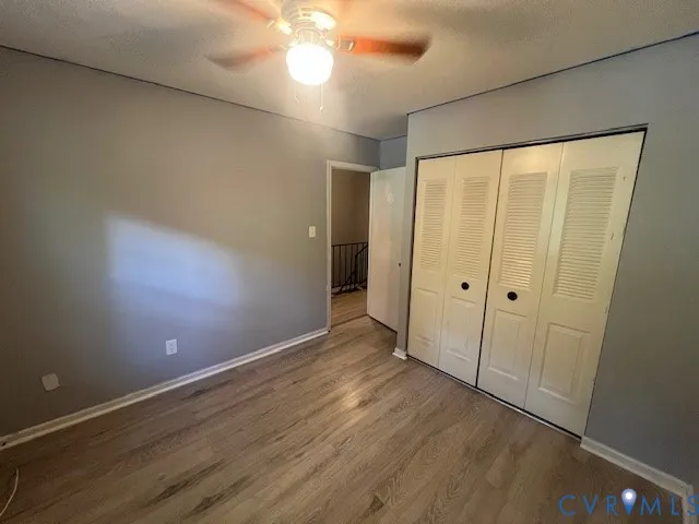 an empty room with wooden floor and fan