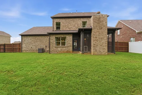 a view of a house with brick walls and a yard with a large tree