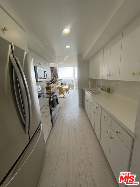 2222 Avenue Of The Stars, Unit 705 Los Angeles, CA 90067 - Photo 12 of 36 a kitchen with granite countertop a refrigerator a sink dishwasher a stove and white cabinets with wooden floor