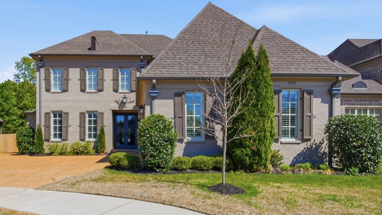 Stately brick facade with contrasting shutters, gabled roofline, and an inviting double-door entry