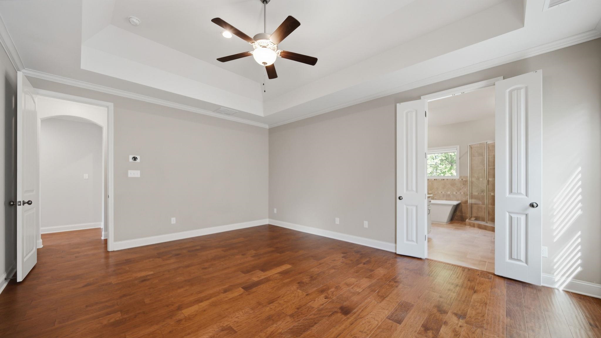 1058 Shanborne Cove Collierville, TN 38017 - Photo 20 of 39 Unfurnished bedroom featuring ornamental molding, arched walkways, dark wood finished floors, a ceiling fan, and connected bathroom