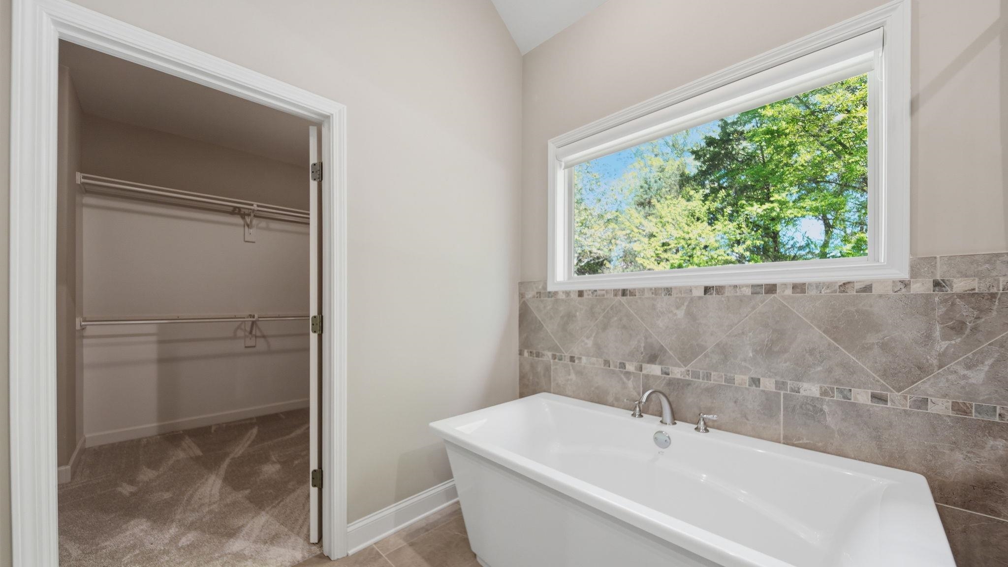 1058 Shanborne Cove Collierville, TN 38017 - Photo 24 of 39 Bathroom with a freestanding bath, a spacious closet, and tile walls