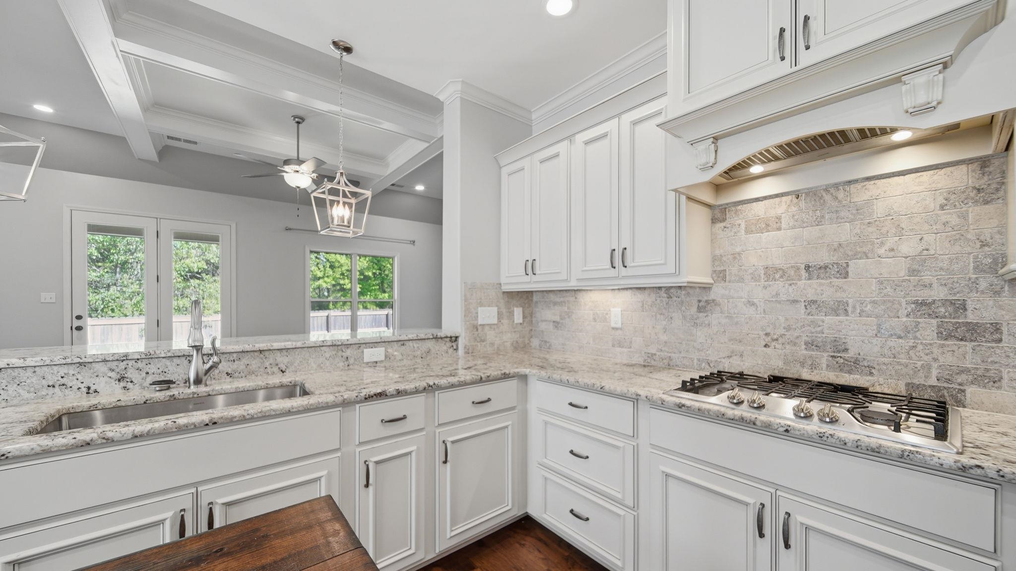 1058 Shanborne Cove Collierville, TN 38017 - Photo 3 of 39 Kitchen featuring white cabinetry, light stone countertops, decorative light fixtures, dark wood-style flooring, and stainless steel gas cooktop