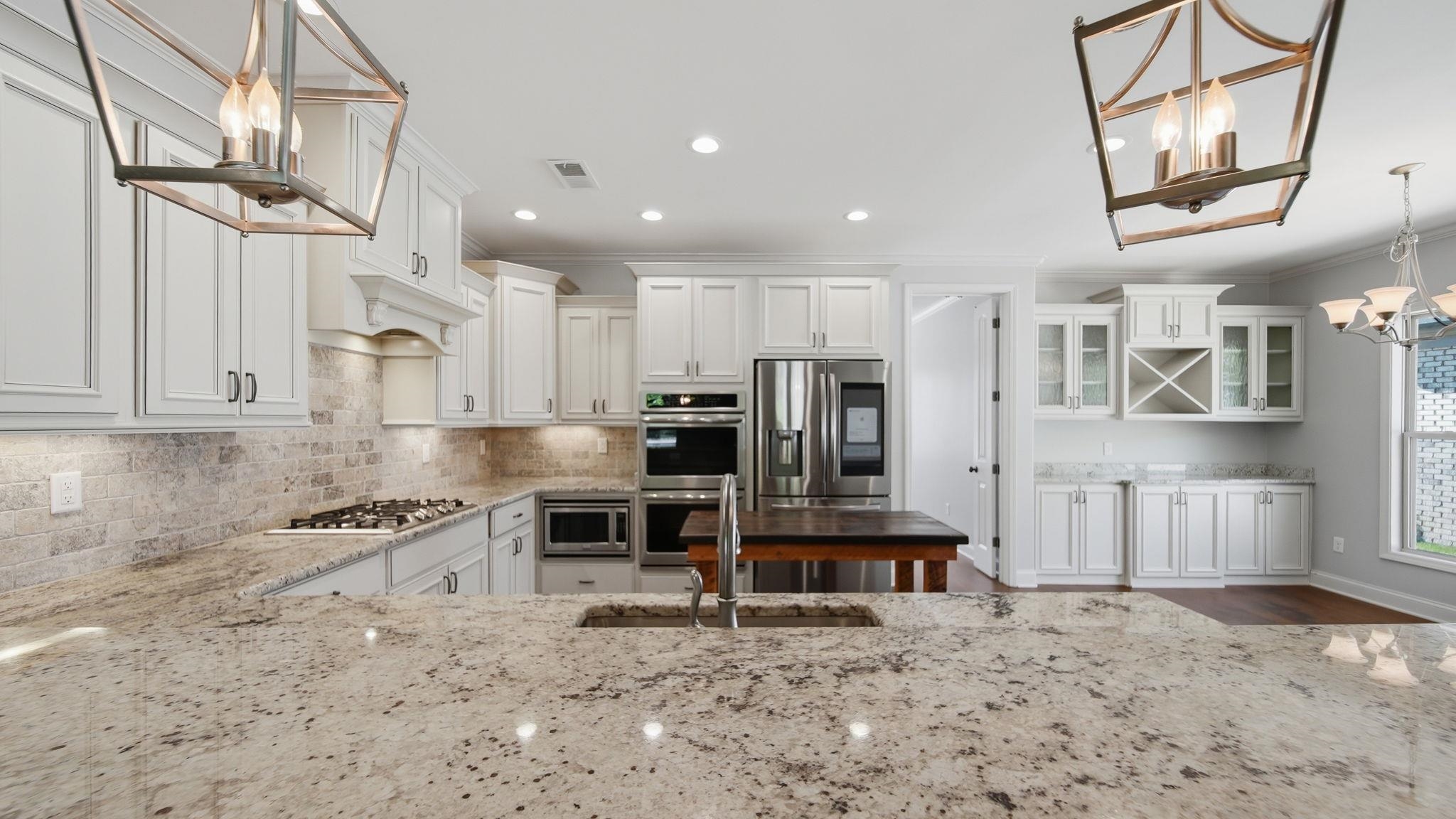 1058 Shanborne Cove Collierville, TN 38017 - Photo 5 of 39 Kitchen featuring a chandelier, white cabinetry, light stone counters, tasteful backsplash, and stainless steel appliances