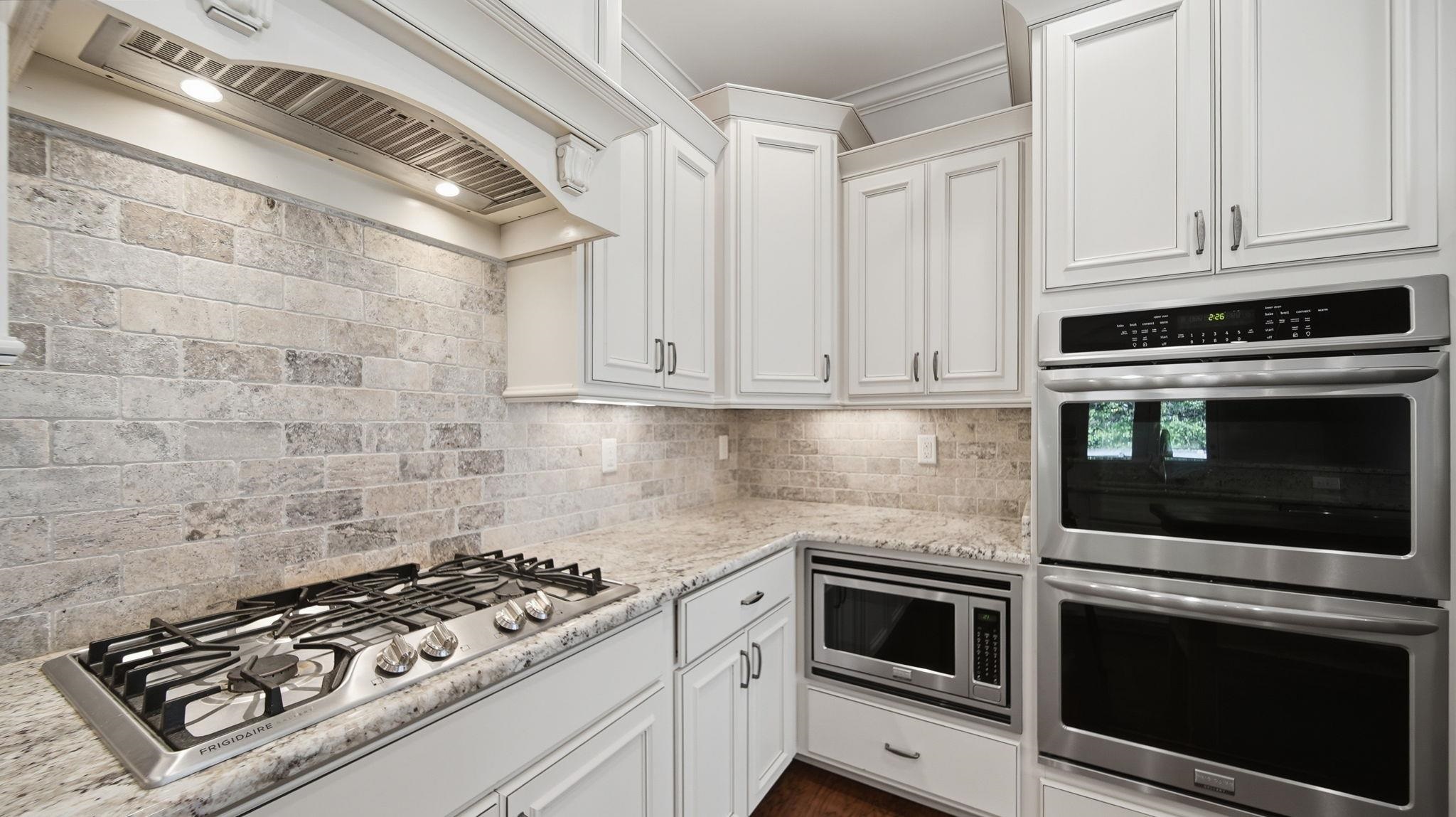1058 Shanborne Cove Collierville, TN 38017 - Photo 6 of 39 Kitchen with stainless steel appliances, white cabinetry, light stone countertops, and backsplash