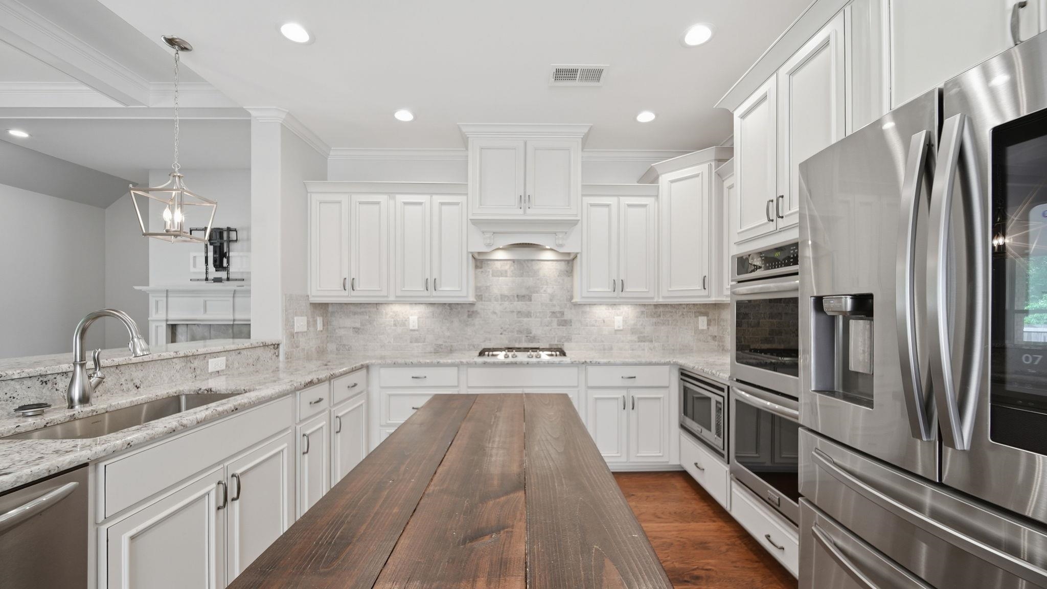 1058 Shanborne Cove Collierville, TN 38017 - Photo 7 of 39 Kitchen with stainless steel appliances, light stone countertops, white cabinetry, ornamental molding, and tasteful backsplash