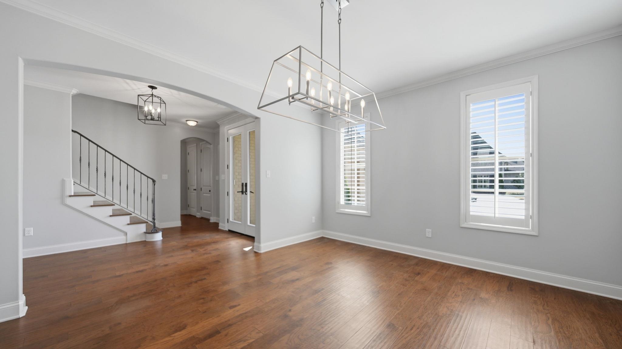 1058 Shanborne Cove Collierville, TN 38017 - Photo 9 of 39 Unfurnished dining area featuring crown molding, arched walkways, a chandelier, and dark wood-style floors
