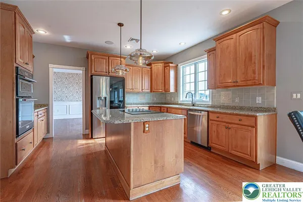 a large kitchen with kitchen island lots of counter space a sink appliances and a large window