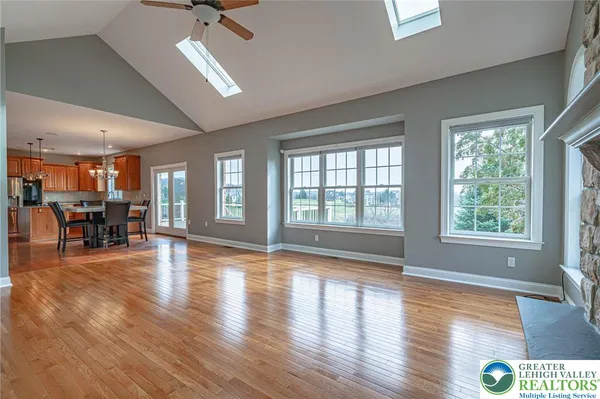 an empty room with wooden floor mirror and windows
