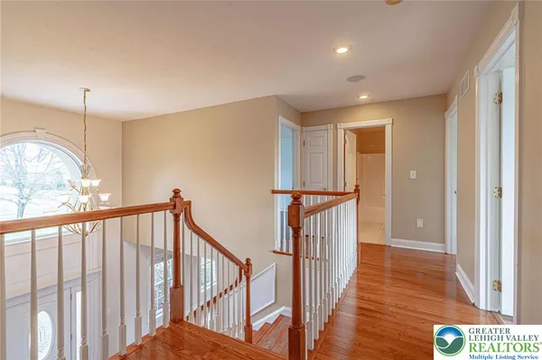 an empty room with wooden floor chandelier and windows