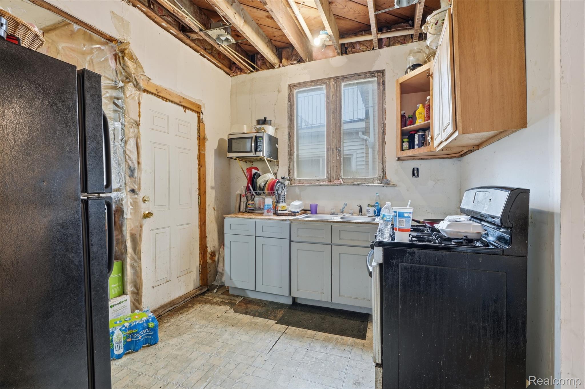 2500 Atkinson Street Detroit, MI 48206 - Photo 7 of 21 Kitchen with range with gas stovetop, freestanding refrigerator, stainless steel microwave, gray cabinetry, and light countertops