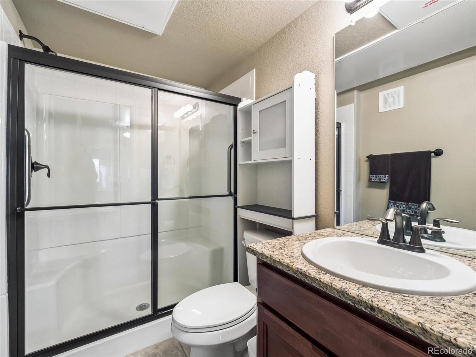 1144 Rockhurst Drive, Unit 107 Highlands Ranch, CO 80129 - Photo 16 of 29 a bathroom with a granite countertop sink toilet and shower
