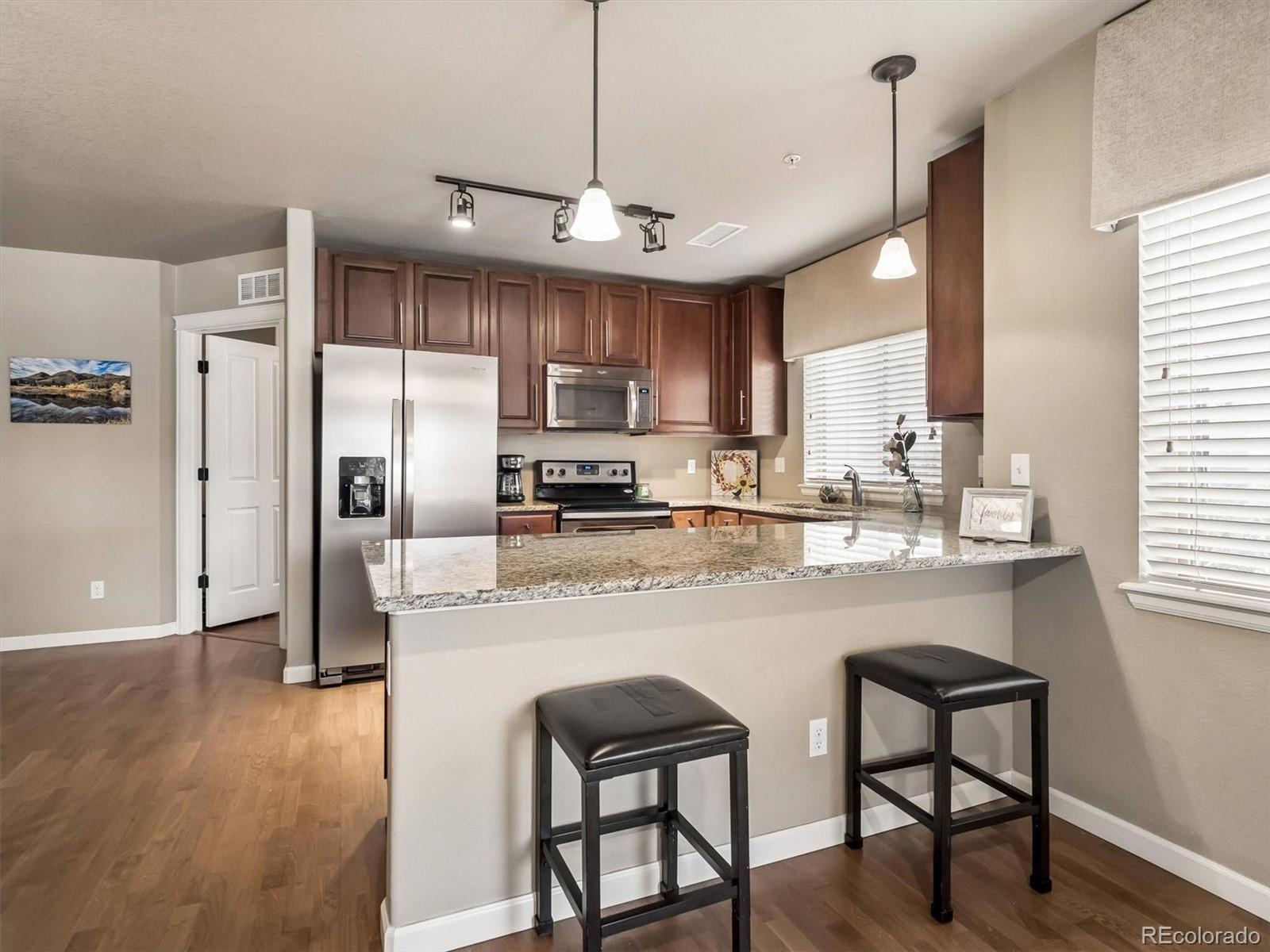 1144 Rockhurst Drive, Unit 107 Highlands Ranch, CO 80129 - Photo 3 of 29 a kitchen with stainless steel appliances granite countertop a refrigerator a sink a stove a dining table and chairs
