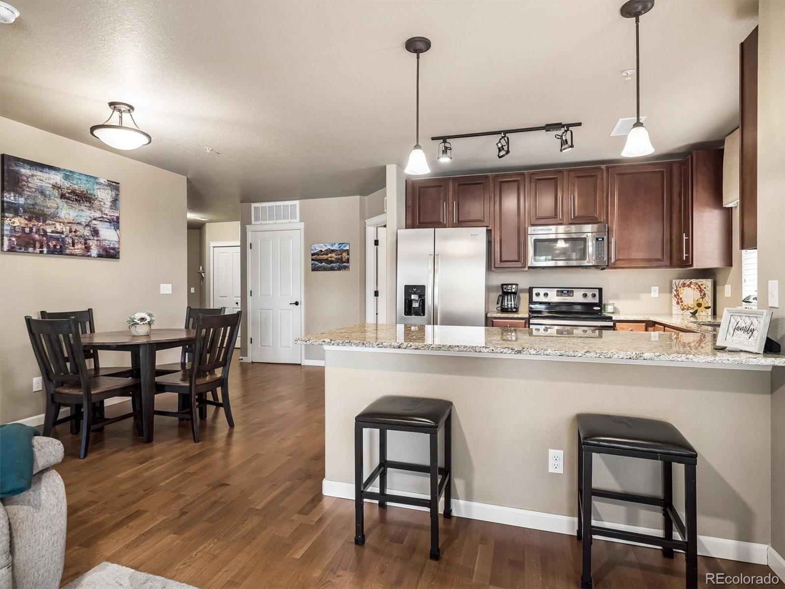 1144 Rockhurst Drive, Unit 107 Highlands Ranch, CO 80129 - Photo 4 of 29 a kitchen with stainless steel appliances granite countertop a stove a refrigerator a kitchen island a dining table and chairs