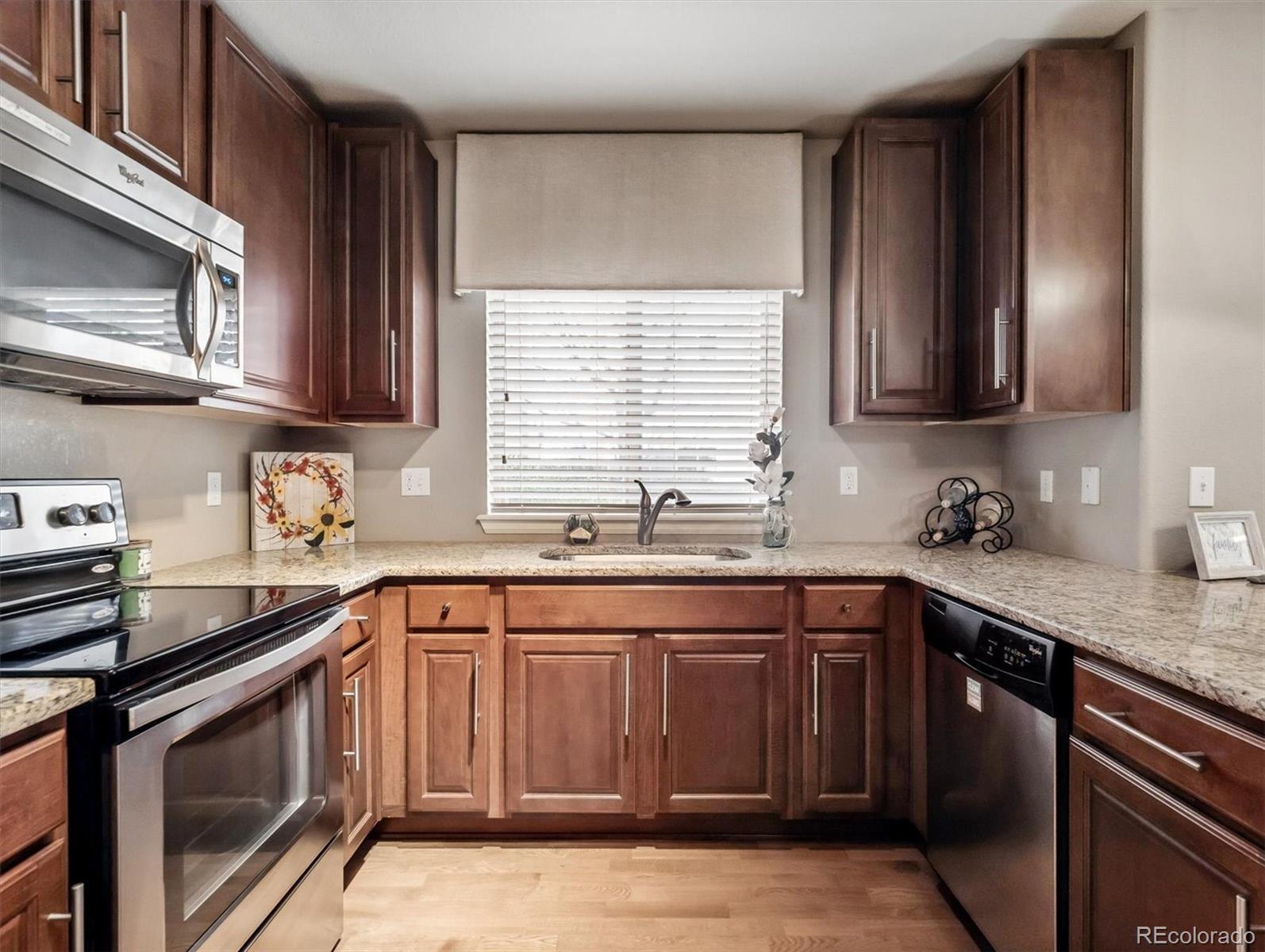 1144 Rockhurst Drive, Unit 107 Highlands Ranch, CO 80129 - Photo 8 of 29 a kitchen with stainless steel appliances granite countertop a sink stove a microwave and cabinets