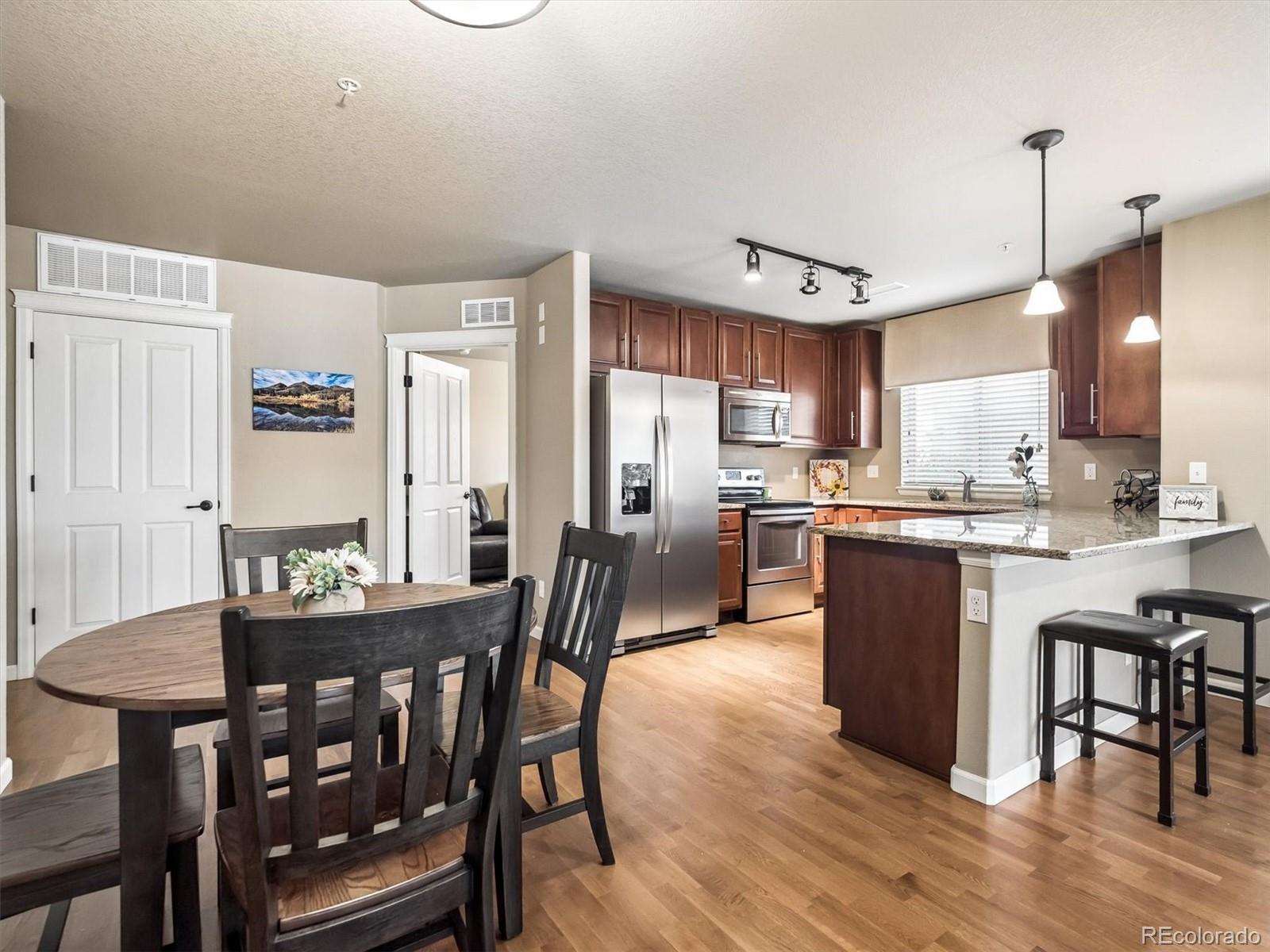 1144 Rockhurst Drive, Unit 107 Highlands Ranch, CO 80129 - Photo 9 of 29 a kitchen with stainless steel appliances granite countertop a kitchen island a stove a table and chairs