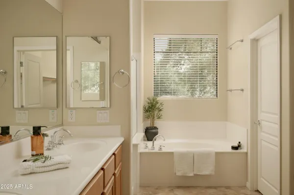 a bathroom with a granite countertop tub sink and mirror