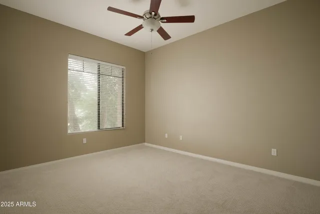 an empty room with windows and fan
