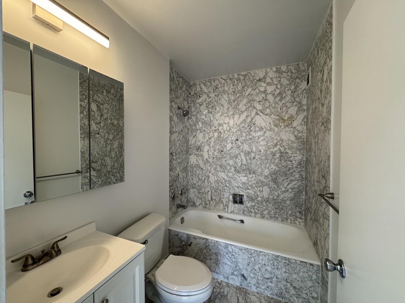 377 Rector Place, Unit 17D Manhattan, NY 10280 - Photo 11 of 15 a bathroom with a bathtub shower sink mirror vanity and toilet