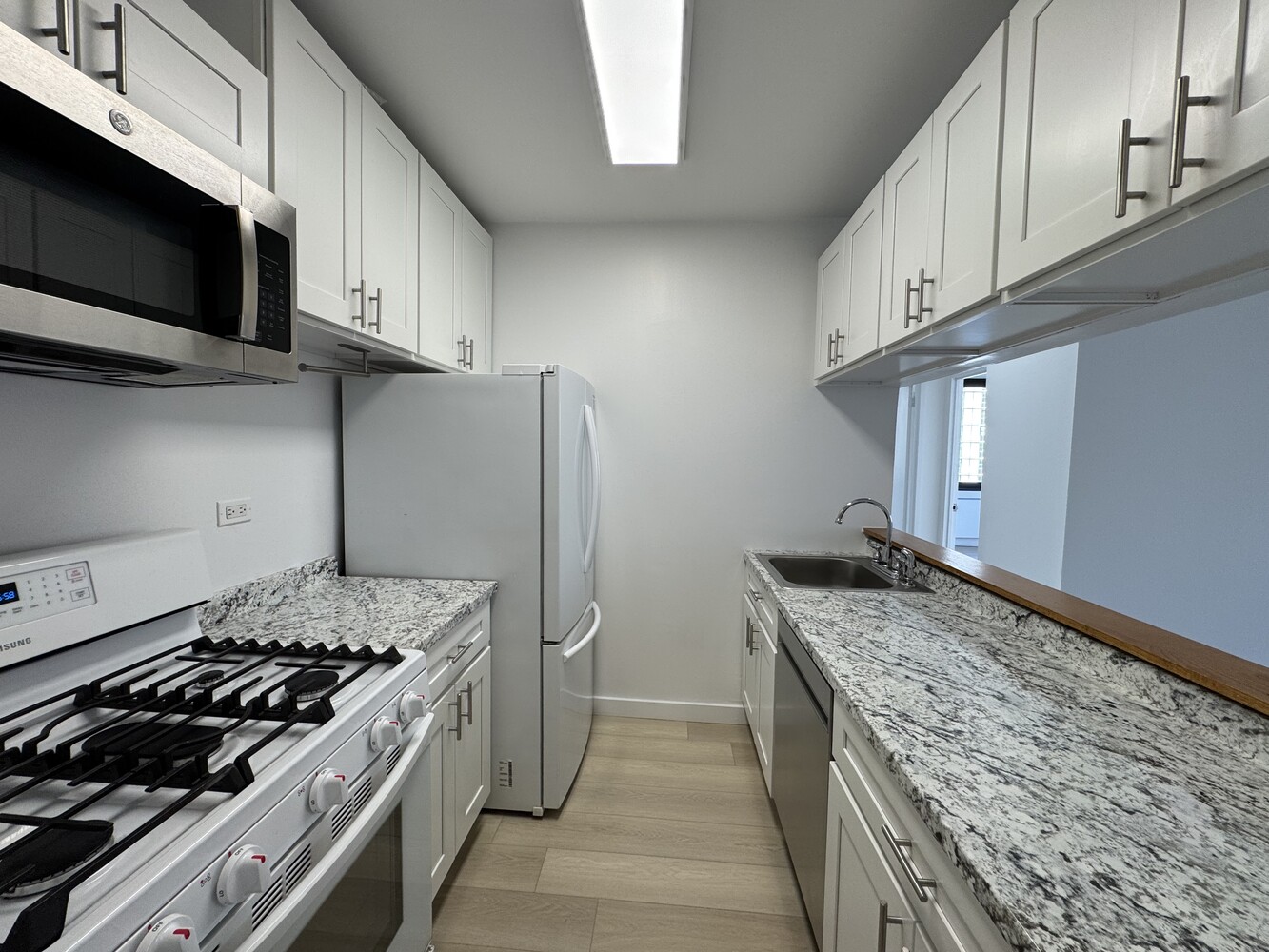 377 Rector Place, Unit 17D Manhattan, NY 10280 - Photo 14 of 15 a kitchen with stainless steel appliances granite countertop a stove and a refrigerator