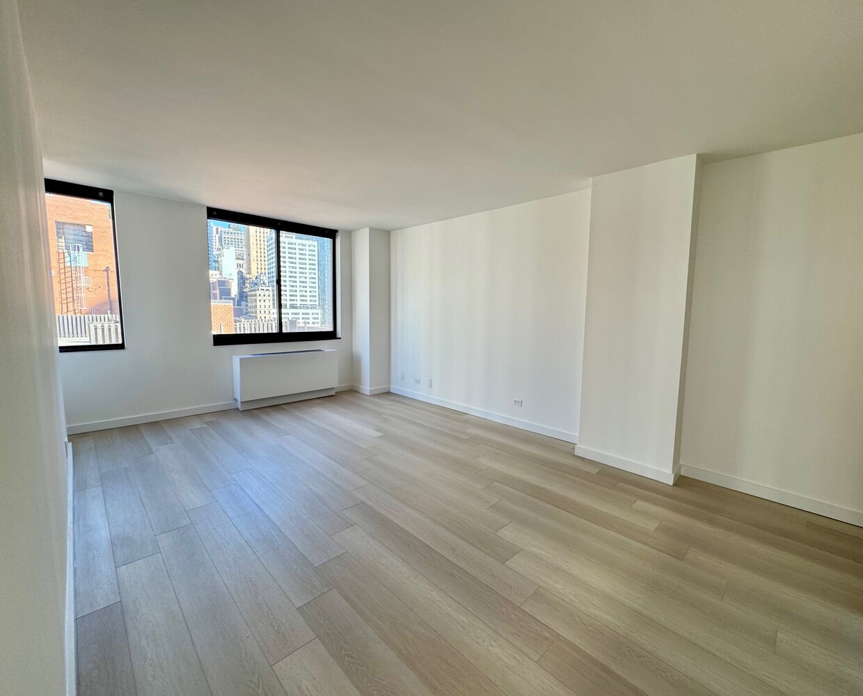 377 Rector Place, Unit 17D Manhattan, NY 10280 - Photo 4 of 15 a view of empty room with wooden floor and fan