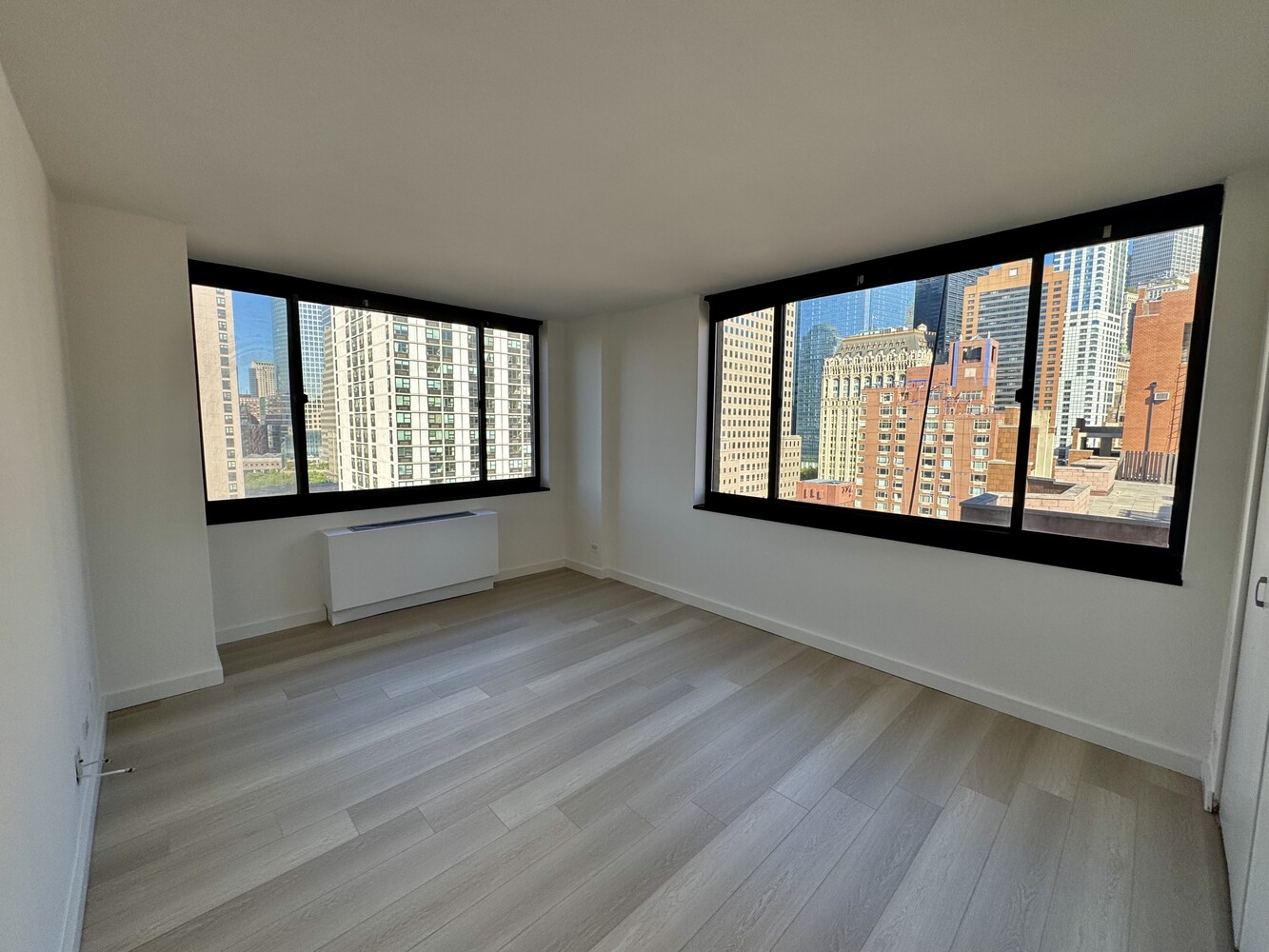 377 Rector Place, Unit 17D Manhattan, NY 10280 - Photo 5 of 15 a view of an empty room with wooden floor and a window