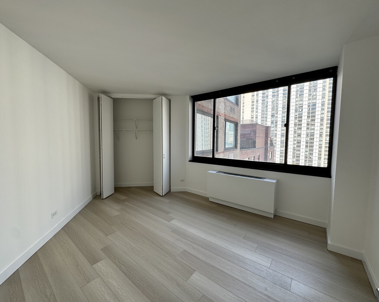377 Rector Place, Unit 17D Manhattan, NY 10280 - Photo 8 of 15 an empty room with wooden floor and windows