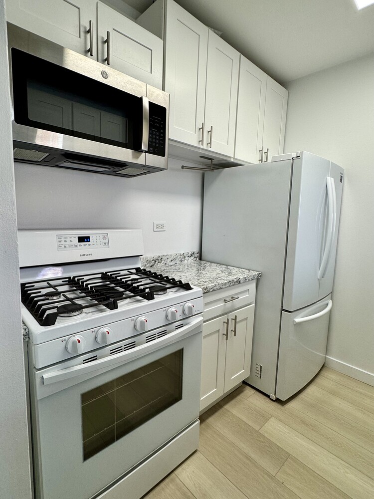 377 Rector Place, Unit 17D Manhattan, NY 10280 - Photo 9 of 15 a kitchen with stainless steel appliances granite countertop a stove and a microwave