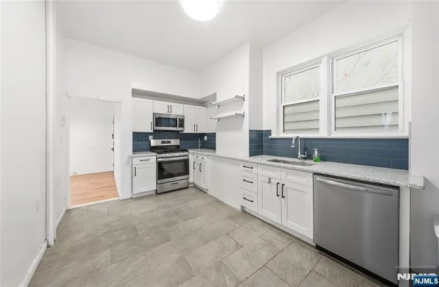 a kitchen with granite countertop white cabinets and stainless steel appliances