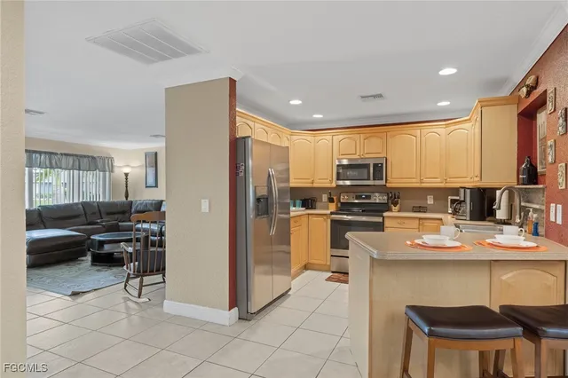 a kitchen with stainless steel appliances granite countertop a refrigerator a stove a sink a dining table and chairs with wooden floor