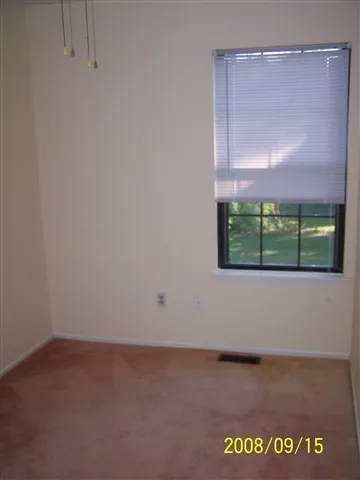 a view of an empty room with a window and a cabinet