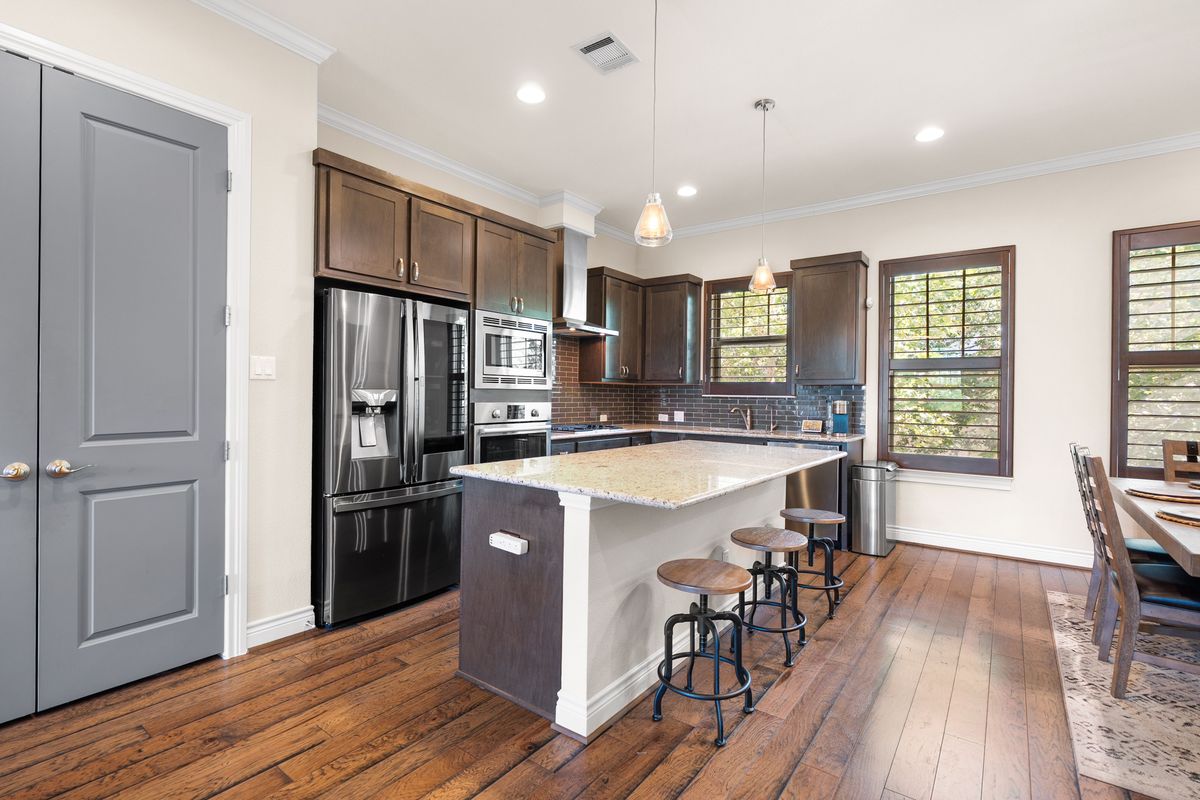 1116 Highknoll Lane Georgetown, TX 78628 - Photo 9 of 36 a kitchen with stainless steel appliances granite countertop a refrigerator a sink dishwasher a stove and a dining table with wooden floor