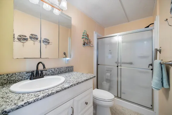 a bathroom with a granite countertop sink toilet and shower