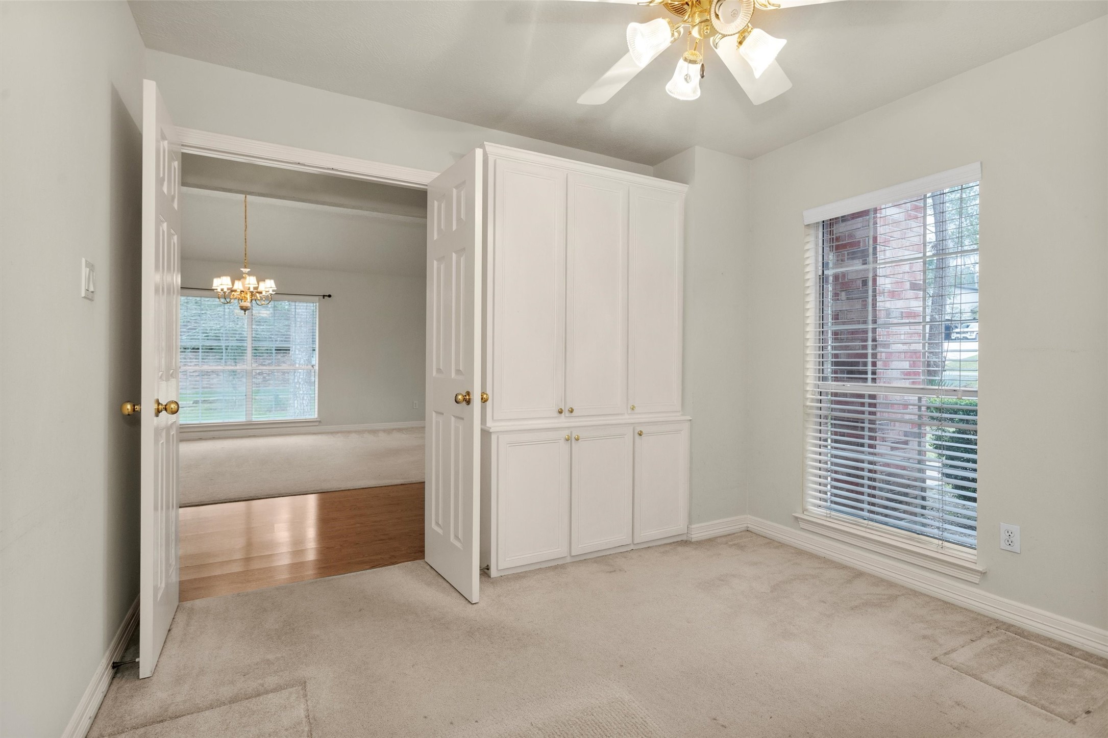 2419 Carriage Ridge Lane Conroe, TX 77384 - Photo 11 of 39 This front room has carpet flooring, a large window with blinds, and built-in white cabinetry. A ceiling fan with lights hangs overhead. Double doors open to the entryway. This could be an office/study/playroom/bedroom or media room.