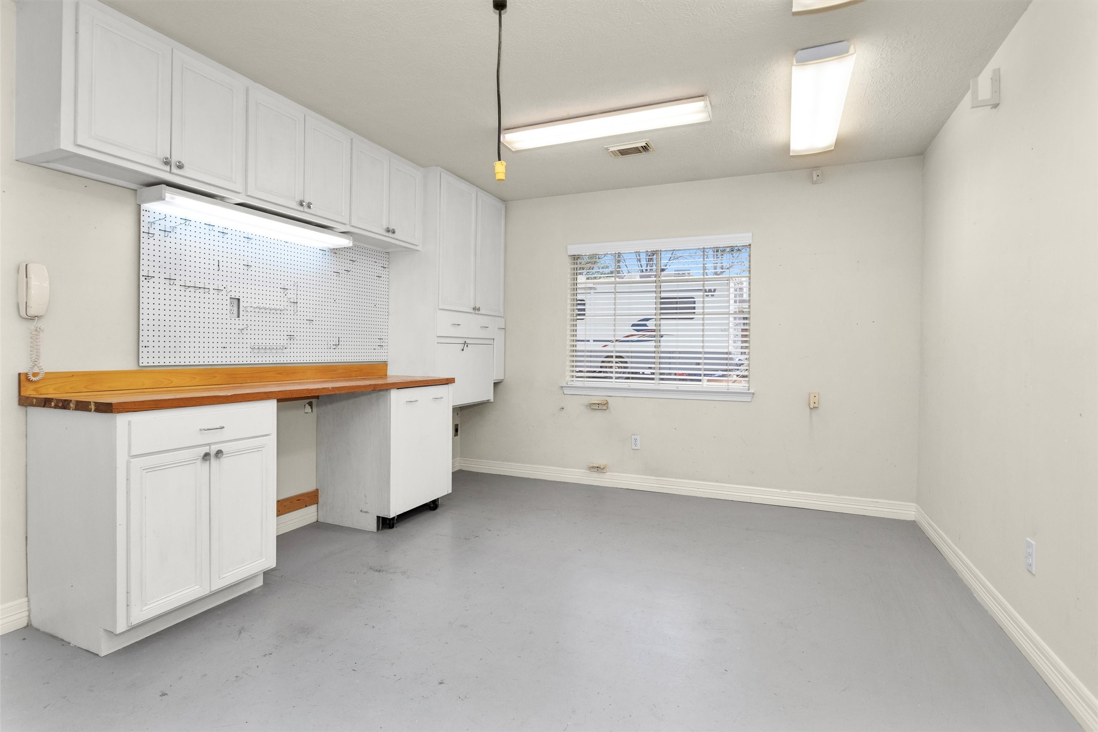2419 Carriage Ridge Lane Conroe, TX 77384 - Photo 31 of 39 This room features a spacious, well-lit converted area is ideal for a workshop or hobby space. It includes ample storage with overhead cabinets and a pegboard for tools, plus a window providing natural light.