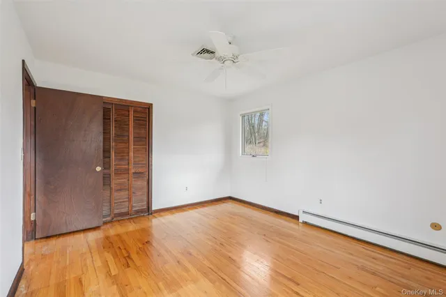 an empty room with a ceiling fan and wooden floor