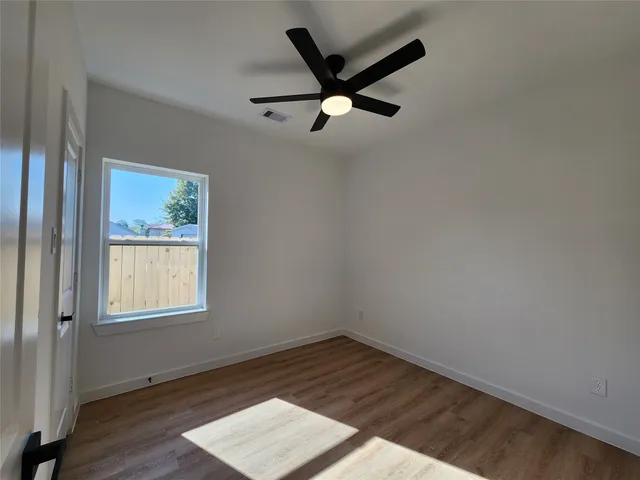 an empty room with wooden floor closet and windows
