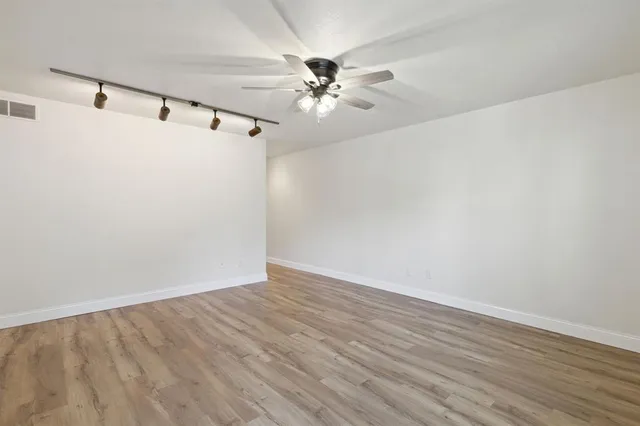 a view of a room with wooden floor and a ceiling fan