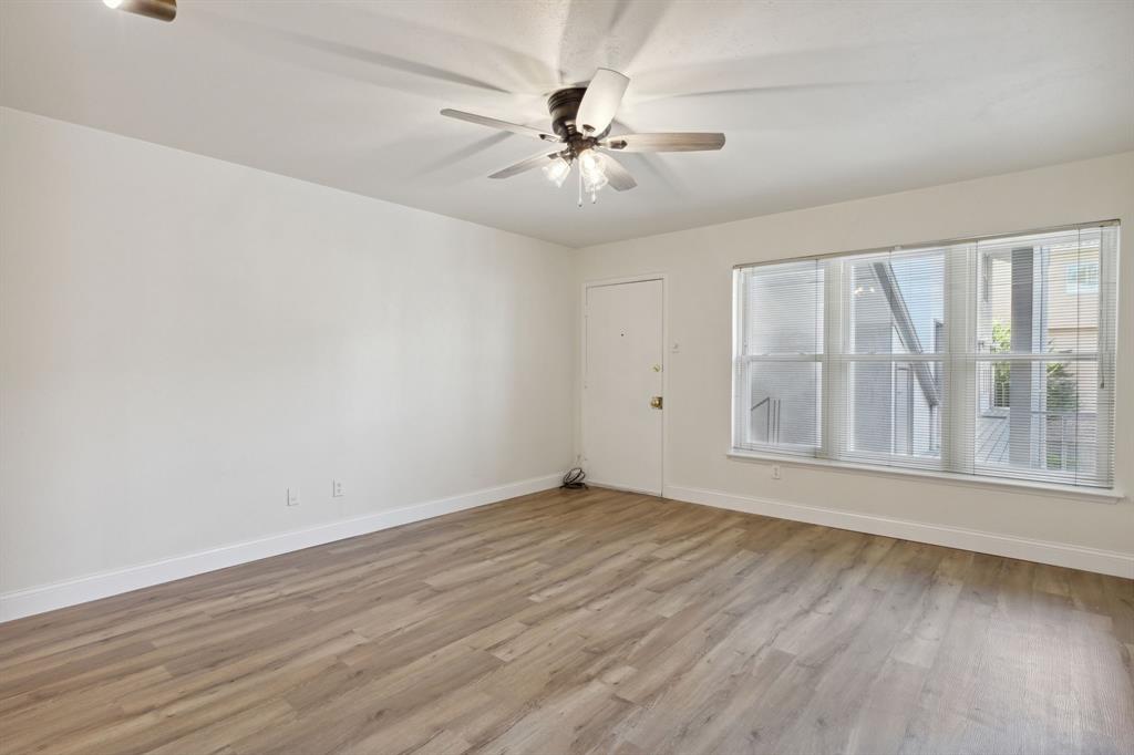 3827 Gilbert Avenue, Unit 214 Dallas, TX 75219 - Photo 5 of 25 an empty room with wooden floor fan and windows