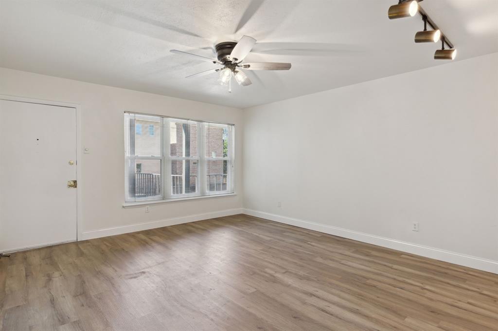 3827 Gilbert Avenue, Unit 214 Dallas, TX 75219 - Photo 6 of 25 a view of an empty room with wooden floor and a window